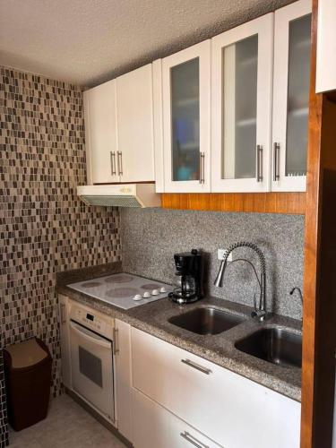 a kitchen with white cabinets and a sink at Hermoso apartamento para vacacionar in Porlamar