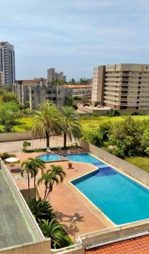 an overhead view of a pool with palm trees and buildings at Hermoso apartamento para vacacionar in Porlamar