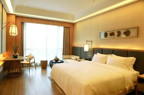 a hotel room with a large bed and a window at Harman Resort Hotel Sanya in Sanya