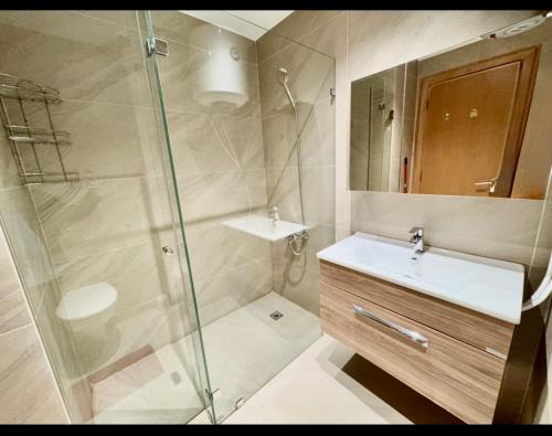 a bathroom with a shower and a sink and a mirror at Amman studio Damac Tower in Amman