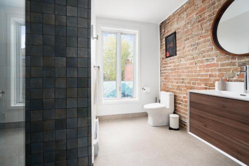 a bathroom with a toilet and a brick wall at MTL Central Stay Apartments in Montréal