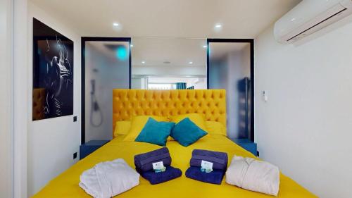 - une chambre avec un lit jaune et des oreillers bleus dans l'établissement Le Majestic, Naturist Village 3 bedrooms 90 m2, au Cap d'Agde
