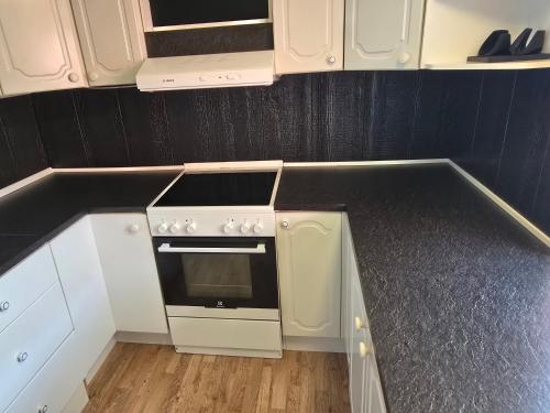 a kitchen with a stove and white cabinets at Rent your own home in Velfjord in Saus