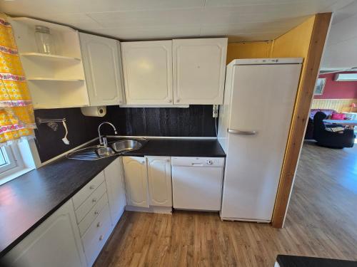 a kitchen with white cabinets and a white refrigerator at Rent your own home in Velfjord in Saus