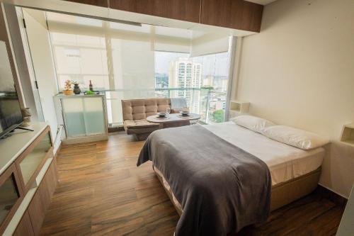 a bedroom with a bed and a large window at 2206 - Studio | alto padrão in Guarulhos