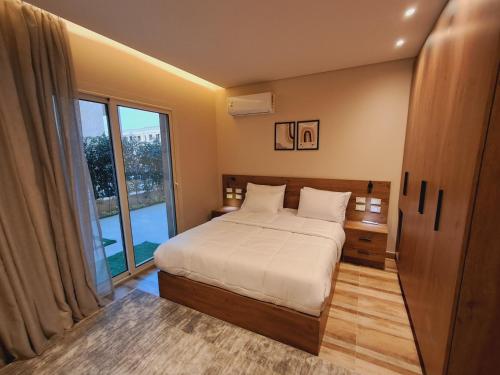 a bedroom with a bed and a large window at شقة فندقية فى الشيخ زايد داخل كمبوند حديقة خاصة ومدخل خاص in Sheikh Zayed