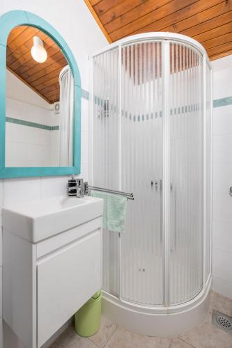 a white bathroom with a shower and a sink at Štalica Little Barn in Mala Učka