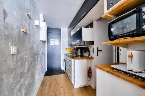 Il comprend une cuisine avec des placards blancs et une télévision murale. dans l'établissement Résidence Le Tourmalet - maeva Home - Studio 6 personnes - Prestige MAE-9911, à La Mongie