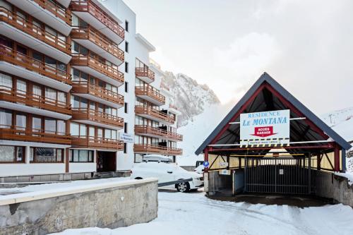 Un bâtiment avec un panneau dans la neige dans l'établissement Résidence Le Montana - maeva Home - Studio 4 personnes - Sélection MAE-0661, à La Mongie
