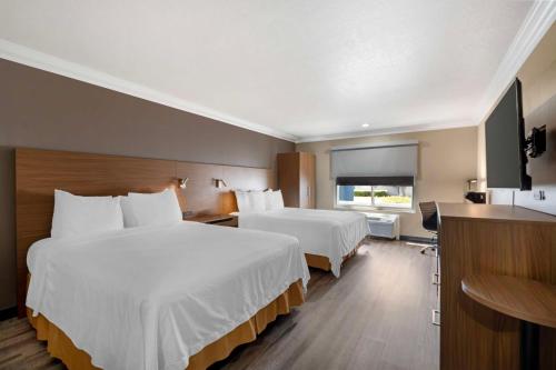 a hotel room with two beds and a television at Best Western Plus Newport Mesa Inn in Costa Mesa
