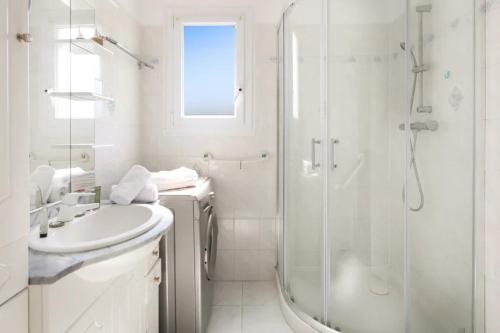 une salle de bain blanche avec une douche et un lavabo dans l'établissement Appartement cosy dans résidence avec piscine et à 2 pas de la mer, à Bandol