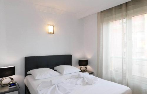 une chambre avec un lit avec des draps blancs et une fenêtre dans l'établissement Appartement 6 personnes au cœur de Cannes - Appartement 4 pièces 6 personnes MAE-0031, à Cannes