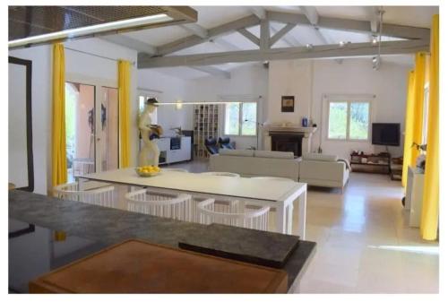 - un grand salon avec une table blanche et des rideaux jaunes dans l'établissement Villa accueillante avec piscine à Seillans, à Seillans