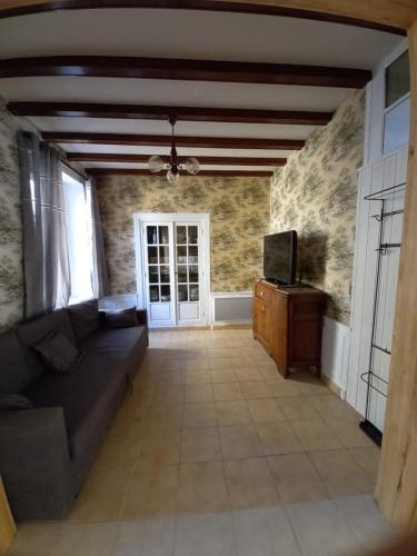 un salon avec un canapé et une télévision dans l'établissement Maison de Famille face à l'église, à Sainte-Mère-Église