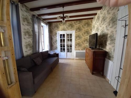 un salon avec un canapé et une télévision dans l'établissement Maison de Famille face à l'église, à Sainte-Mère-Église