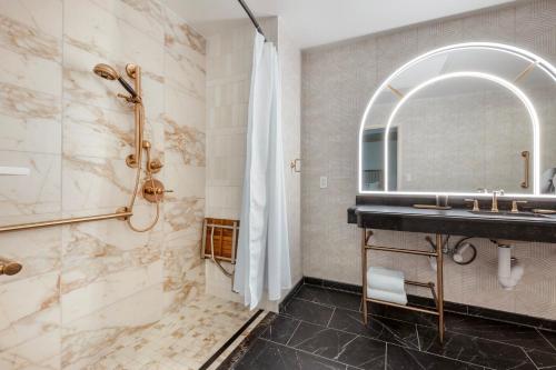 a bathroom with a sink and a shower and a mirror at Omni Severin Hotel in Indianapolis
