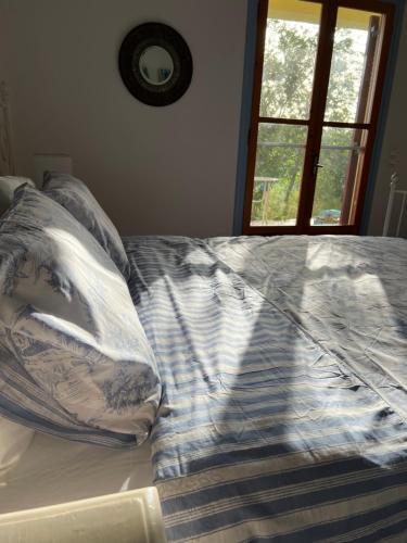a bed with pillows on it with a window at Peaceful home amongst olive groves by the sea in Koroni