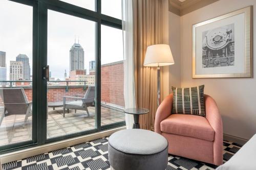 a living room with a chair and a large window at Omni Severin Hotel in Indianapolis