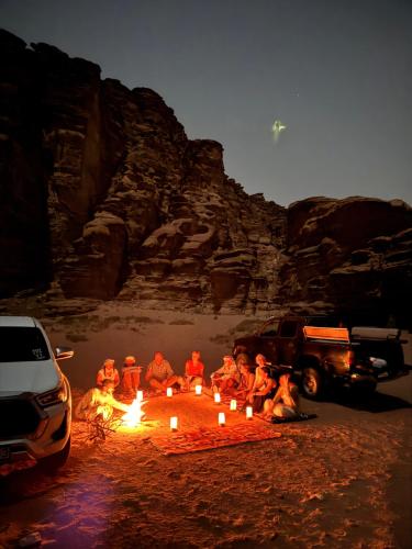 a group of people sitting around a fire in the desert at Rum Angel Camp in Wadi Rum