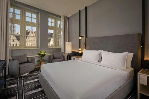 a bedroom with a large white bed and a chair at Ghent Marriott Hotel in Ghent