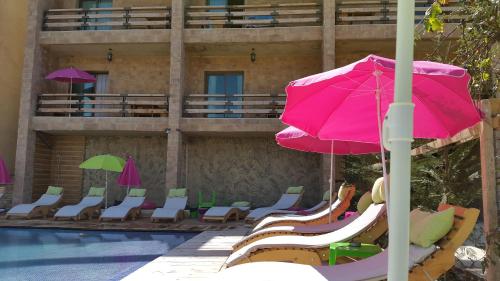 a group of chairs and umbrellas next to a pool at Villetta di Faraya in Fārayyā