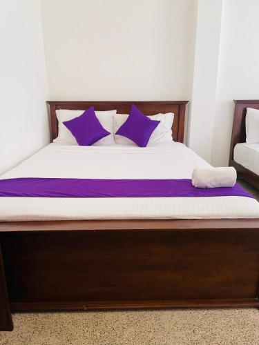 a bed with purple and white pillows on it at Villa Lavish in Kandy