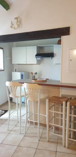 une cuisine avec des armoires blanches et une table et des chaises dans l'établissement Gîte Thym, à Maubec