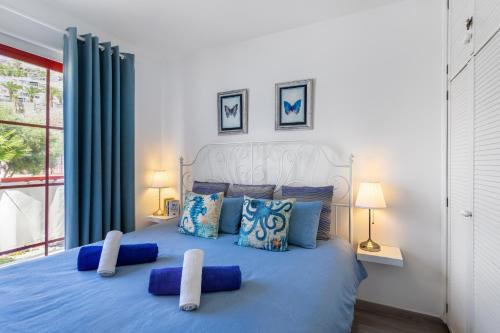 a bedroom with a blue bed with blue pillows at Ocean Breeze in Mogán