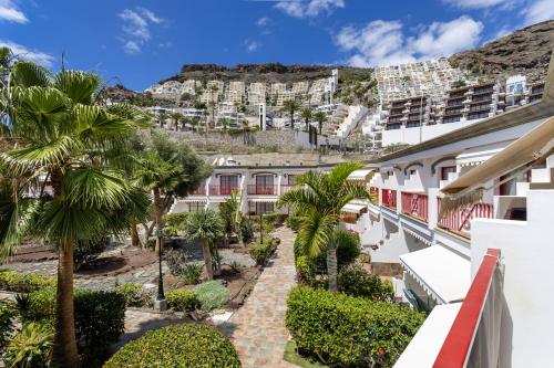 an apartment building with palm trees and a mountain at Ocean Breeze in Mogán