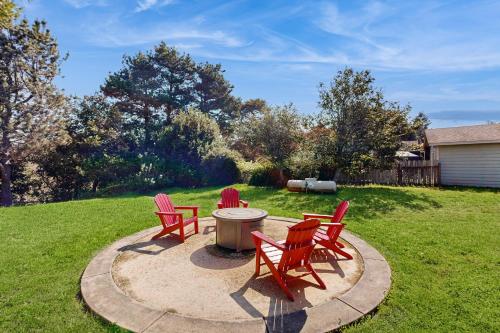 three red chairs sitting around a fire pit in a yard at Park View in Fort Bragg