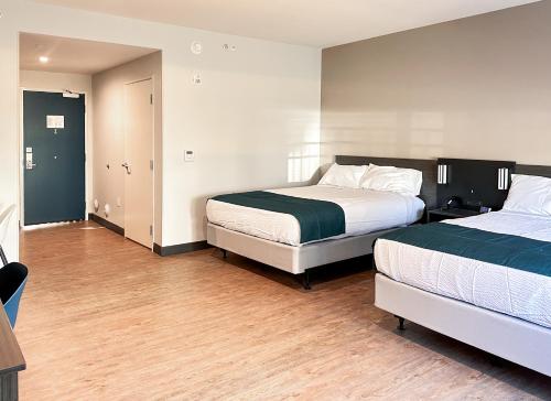 a bedroom with two beds and a wooden floor at Studio 6 Richmond-Airport in Sandston