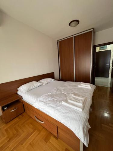 a bedroom with a large bed with white sheets at Apartman Marina in Podgorica