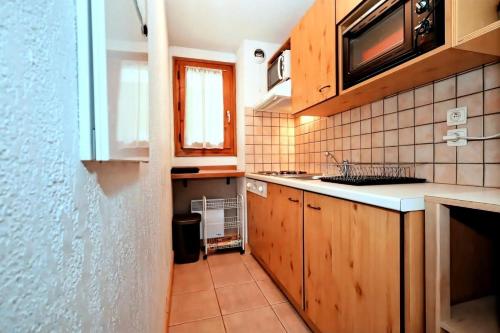 La cuisine est équipée de placards en bois, d'un évier et d'un four micro-ondes. dans l'établissement Résidence Les Sapins - Les Sapins 2 MAE-0514, aux Houches