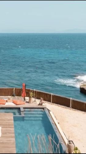 une piscine avec l'océan en arrière-plan dans l'établissement La petite crique, à Sausset-les-Pins