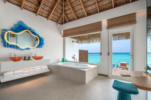 a bathroom with a tub and a view of the ocean at W Maldives in Fesdu Island