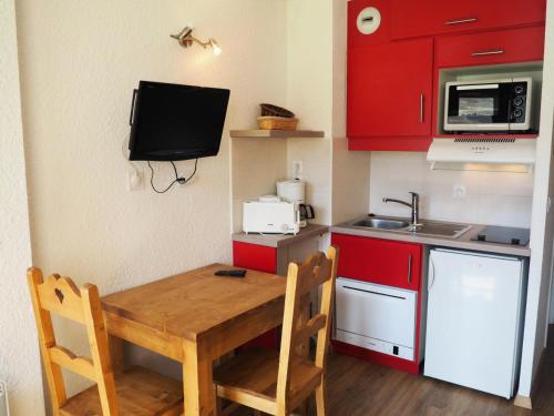 une petite cuisine avec des placards rouges et une table en bois dans l'établissement Résidence Asters B2 - Studio lumineux · Proche des pistes de ski · Balcon MAE-3424, aux Menuires