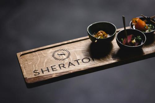 a wooden tray with three bowls of food on it at Sheraton Grand Warsaw in Warsaw