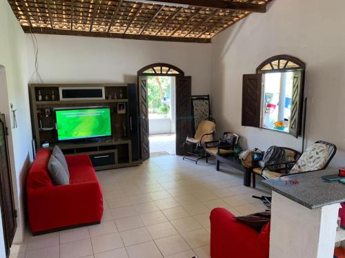 a living room with a tv and red chairs at Chácara Pedacinho do Duro - Matapuã in Aracaju