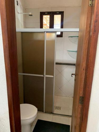 a bathroom with a toilet and a glass shower door at Chácara Pedacinho do Duro - Matapuã in Aracaju