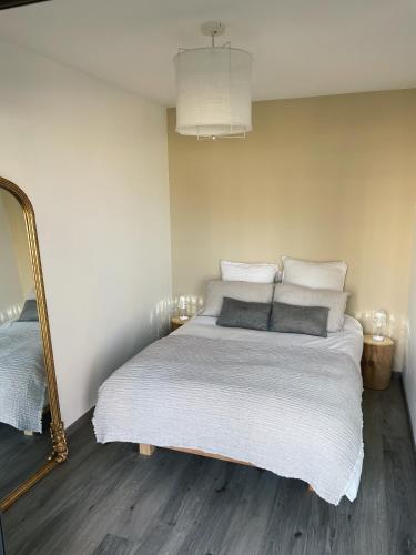 une chambre avec un lit avec des draps blancs et un miroir dans l'établissement Sublime appart avec Jardin - 5 mn à pied des halles et plages, à Dinard