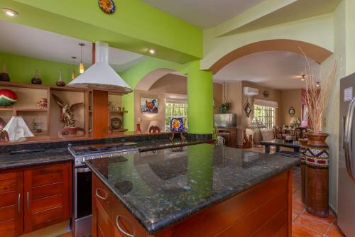 a large kitchen with green walls and a large island at The Bamboo Manor by Andiani Travel in Lafitte