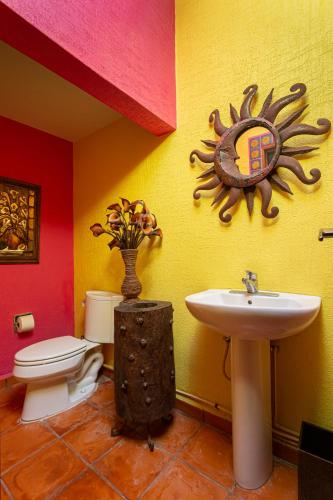 a bathroom with a toilet and a sink with a sun on the wall at The Bamboo Manor by Andiani Travel in Lafitte