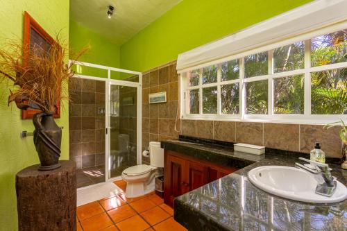 a green bathroom with a sink and a toilet at The Bamboo Manor by Andiani Travel in Lafitte