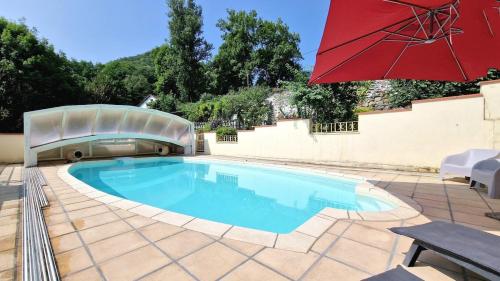 - une piscine avec un parasol rouge et une table dans l'établissement Duplex spacieux avec piscine, à Mauléon-Barousse