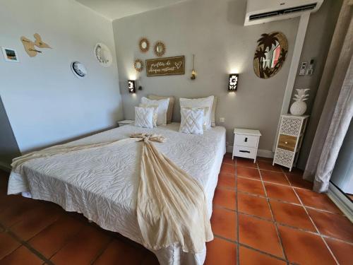 une chambre avec un lit avec des draps blancs et des oreillers dans l'établissement L'oiseau du Paradis vue mer Studio a Saint Francois a 100 m de la plage, à Saint-François