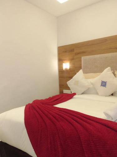 a bedroom with a bed with a red blanket on it at Hôtel Mechouar Plaza in Essaouira