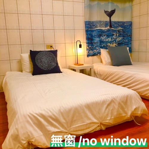 a bedroom with two beds and a painting on the wall at Liuqiu Cozy Room in Xiaoliuqiu