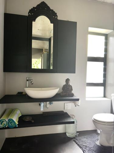 a bathroom with a sink and a mirror at Noordhoek Wellness Pilates in Noordhoek