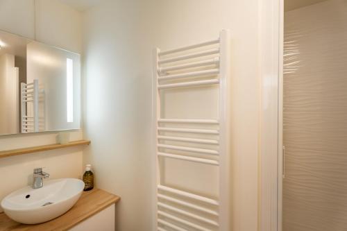 une salle de bain blanche avec un lavabo et un miroir dans l'établissement Escapade tranquille à Vannes, charme et confort, à Vannes