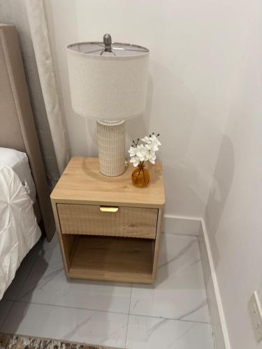 a nightstand with a lamp and a vase of flowers on it at City Abode Kingston Jamaica in Kingston